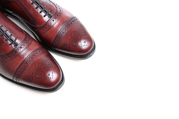 A pair of oxblood leather mens dress shoes on white with copy space