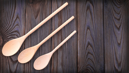 three wooden spoons on a dark wood table with copy space