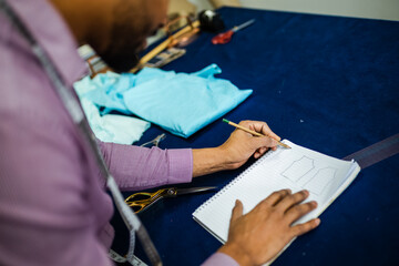 Male African American tailor is making a sketch in his atelier.