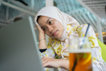 young businesswoman wearing a hijab. Sitting with a dizzy gesture or thinking. In a cafe, work...