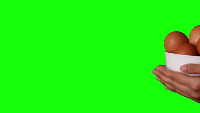 horizontal panning shot of a white bowl of egg in hand green screen background