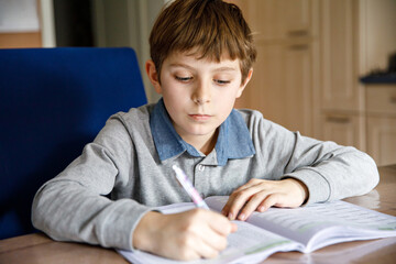 Upset school kid boy making homework during quarantine time from corona pandemic disease. Crying...