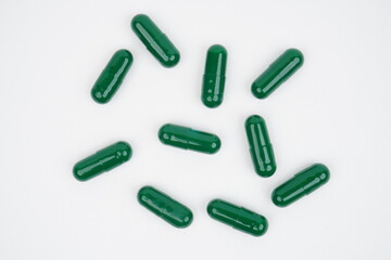 Top view of green pill capsules on white background