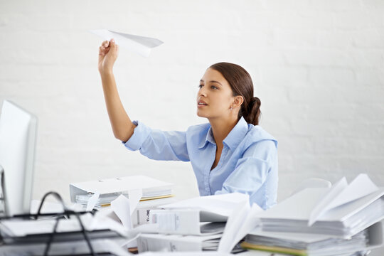 Corporate, businesswoman and paper plane at desk, sitting and thinking while working. Employee and paperwork with files in professional workspace, procrastination and avoid with distraction game