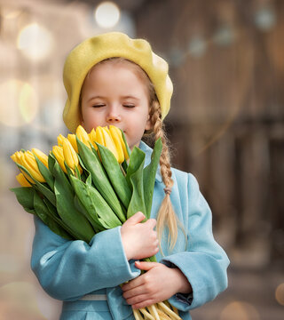 Portrait of a happy girl with a bouquet of yellow tulips on a walk in spring. Flowers for International Women's Day.