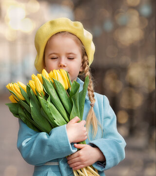 Portrait of a happy girl with a bouquet of yellow tulips on a walk in spring. Flowers for International Women's Day.