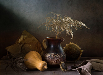 Modern still life with a pumpkin and a dry branch in a clay jug on a dark background © 02irina