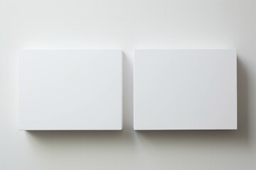 Two mockup white square canvases hanging on a white wall. - obrazy, fototapety, plakaty
