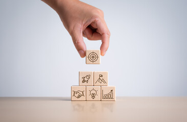 Business goals and marketing strategies. Economic analysis, Company development and success. Wooden cube blocks stack with target and strategy icons. Man holding target icon on wooden lock.