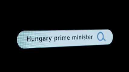 Shot of monitor screen. Pixel screen with animated search bar, keywords Hungary Prime Minister typed in, browser bar with magnifying glass and text headline.