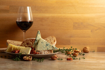 Cheese, bread, red wine, and walnuts on a kitchen table.