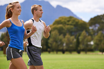 Man, woman and running for exercise on field with smile for speed, wellness and training in summer. People, coach or personal trainer with runner for workout, fitness and together on grass for health