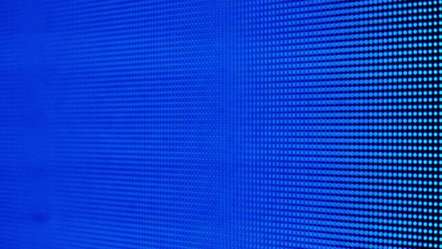 Digital pixel LED screen with colorful neon light footage changing colors blue red green on loop. Close up shot of screen panel background.