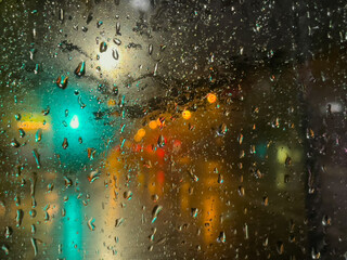 Rain bokeh road lights. Abstract shot of evening city traffic bokeh. Multicolored lights of the evening city and passing cars through a wet rainy window.