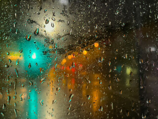 Rain bokeh road lights. Abstract shot of evening city traffic bokeh. Multicolored lights of the evening city and passing cars through a wet rainy window.