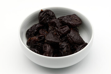 Dried plums in a white bowl isolated on white background