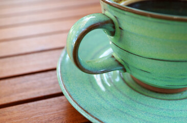 Hot coffee in a green ceramic cup isolated on wooden table