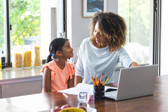 Biracial mother assists a young daughter with schoolwork at home