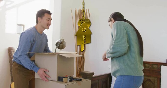 Animation of golden key and house over diverse couple carrying cartons at home