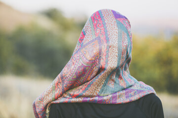 Portrait of an adult woman with a scarf on her head that covers her face in an autumn landscape. Visualization of a psychological problem and analogy of destructive behavior
