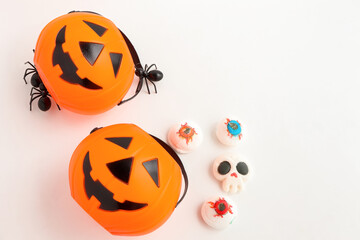 Halloween Jack o Lantern pumpkin bucket, Mashmallow in shape skull, candies and spiders on white background. Trick or treat . Flat lay, top view
