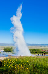 A geyser in a field with old faithful in the background