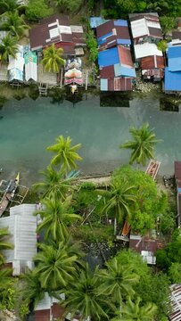 Aerial survey of traditional fishing boat and fishermen village. Cold spring river with clear water in Surigao del Sur. Philippines. Vertical view.