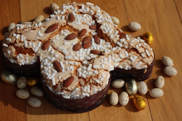 Colomba Pasquale. Sweet Easter cake with chocolate eggs wrapped in foil. Italian traditional pastry on wooden table