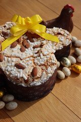 Colomba Pasquale. Sweet Easter cake with dark chocolate hen and eggs wrapped in foil. Italian traditional pastry on wooden table