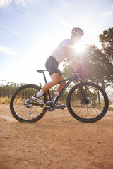 Cyclist, man and bicycle ride in nature, hill and mountain biking in countryside. Male person, freedom and lens flare for fitness or exercise, hobby and sports for outdoor adventure and off road