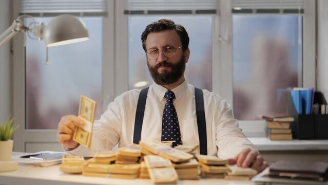 Success, successful businessman, big earnings concept. Rich man sits in chair and admires and displays a lot of money USD on his desk. Vain and arrogant banker or broker enjoys big earnings