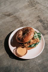 A plate of bagel burger with chicken parmesan with spaghetti, side salad, breaded, fried, and topped with sauce and cheese