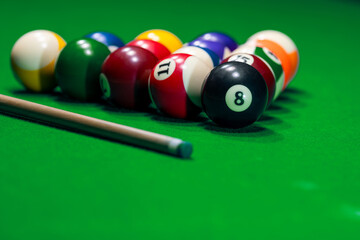 Many colorful billiard balls and cue on green table - 746311751