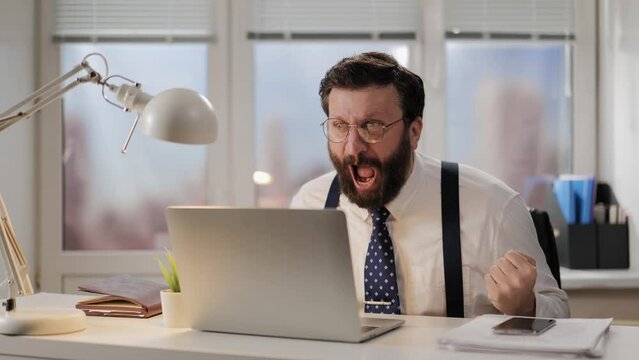 Rage, scream, failure concept. Irritated and aggressive man shouts at computer being very upset after bad news. Mad office worker is furious