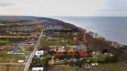 A drone captures Gąski beach, West Pomeranian Voivodeship, Poland, featuring a red brick lighthouse. © Grzegorz
