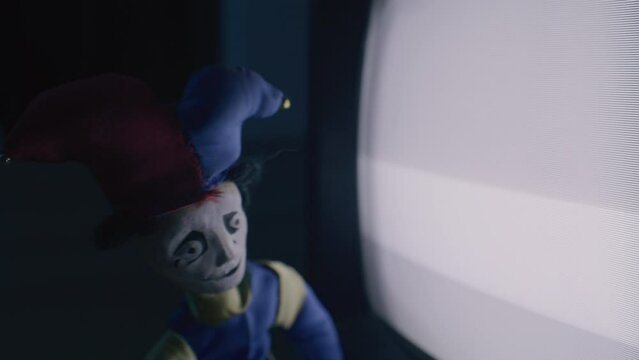Scary old toy clown watching noise in an old TV.