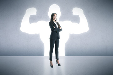 A businesswoman stands confidently with her arms crossed, casting a shadow of a muscular...