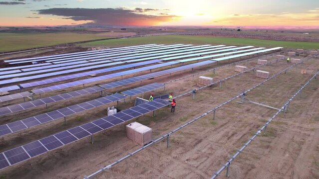 Employees and engineer mounting a Solar Panel over metal frame parts on a large Solar Power Station under construction from Drone point of view producing solar electric energy. Agrivoltaics concept