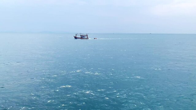 Traditional Small fishing boats are sailing and pulling small boat on the blue sea, Thailand 