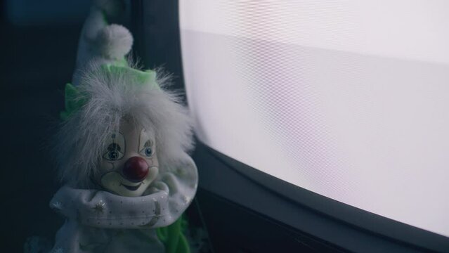 Scary old toy clown watching a broken TV.