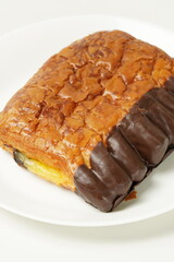 Indulge in our delectable chocolate banana pastry, featuring a rich blend of sweet banana cream and chocolate, encased in a crisp chocolate-covered shell. Photographed against a white backdrop.