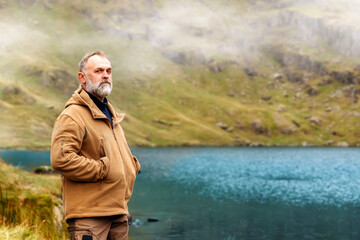 Fototapeta premium Bearded Man reaching the destination and on the top of mountain at sunset on autumn day Travel Lifestyle concept The national park Lake District in England