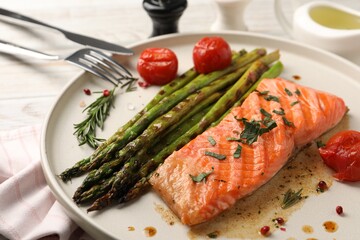 Tasty grilled salmon with tomatoes, asparagus and spices served on table, closeup