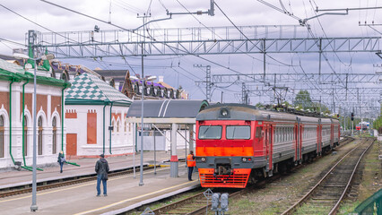 Obraz premium Electric transport on the railway. Contact power lines for commuter trains. People get on an electric train on the platform. Railway tracks at the railway station.Transportation of passengers by train