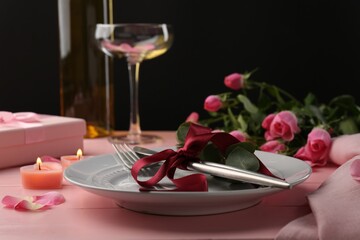 Place setting with roses and candles on pink wooden table, closeup. Romantic dinner