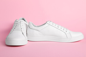 Pair of stylish white sneakers on pink background