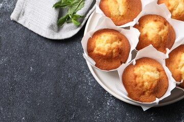 Delicious sweet muffins on black textured table, top view. Space for text