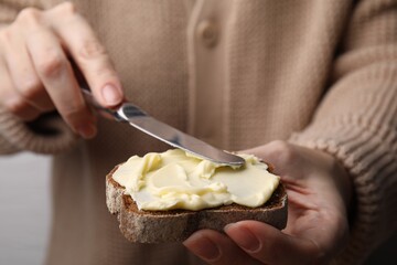 Woman spreading butter onto bread, closeup view