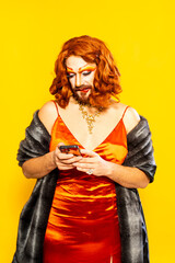 Drag queen in vibrant red dress sends text message against yellow backdrop