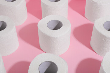 Many soft toilet paper rolls on pink background, closeup